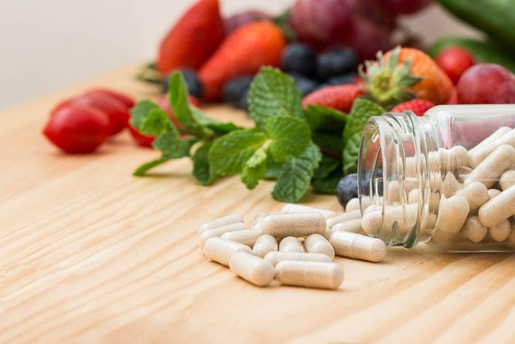 Vitamins supplements in bottle on wooden table.